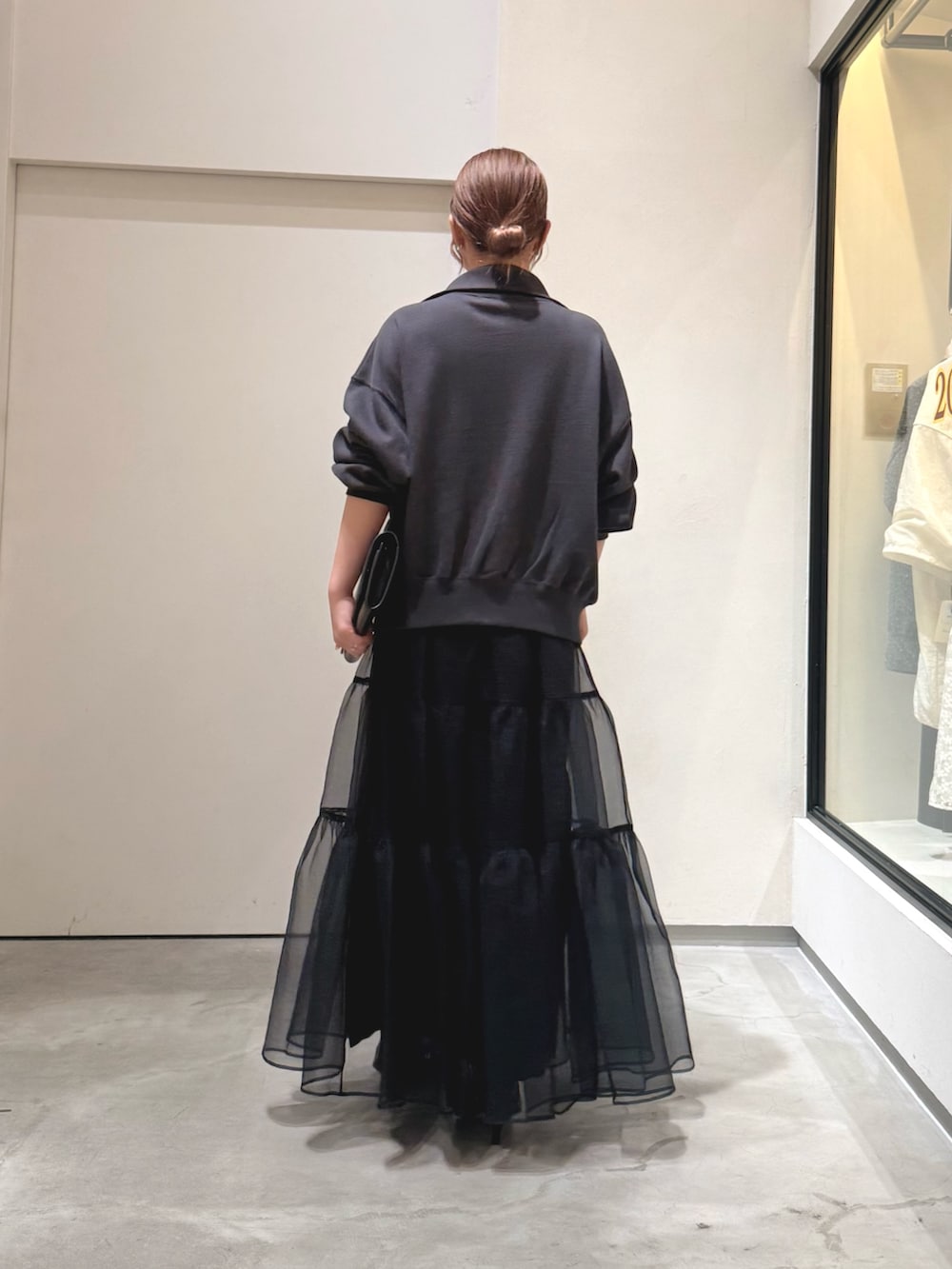 グレー系のスウェット、ブラック系のクラッチバッグ、ブラック系のスカートを着用したレディースの夏コーディネートの3枚目の写真