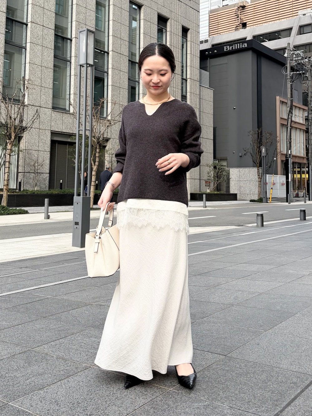 グレー系のニット/セーター、ホワイト系のシャツ/ブラウス、ホワイト系のスカートを着用したレディースの春コーディネートの2枚目の写真