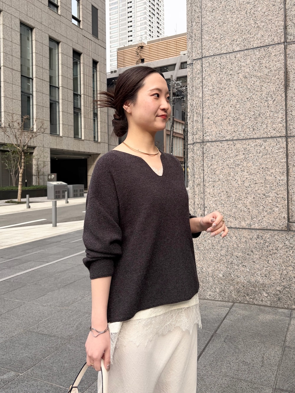 グレー系のニット/セーター、ホワイト系のシャツ/ブラウス、ホワイト系のスカートを着用したレディースの春コーディネートの5枚目の写真