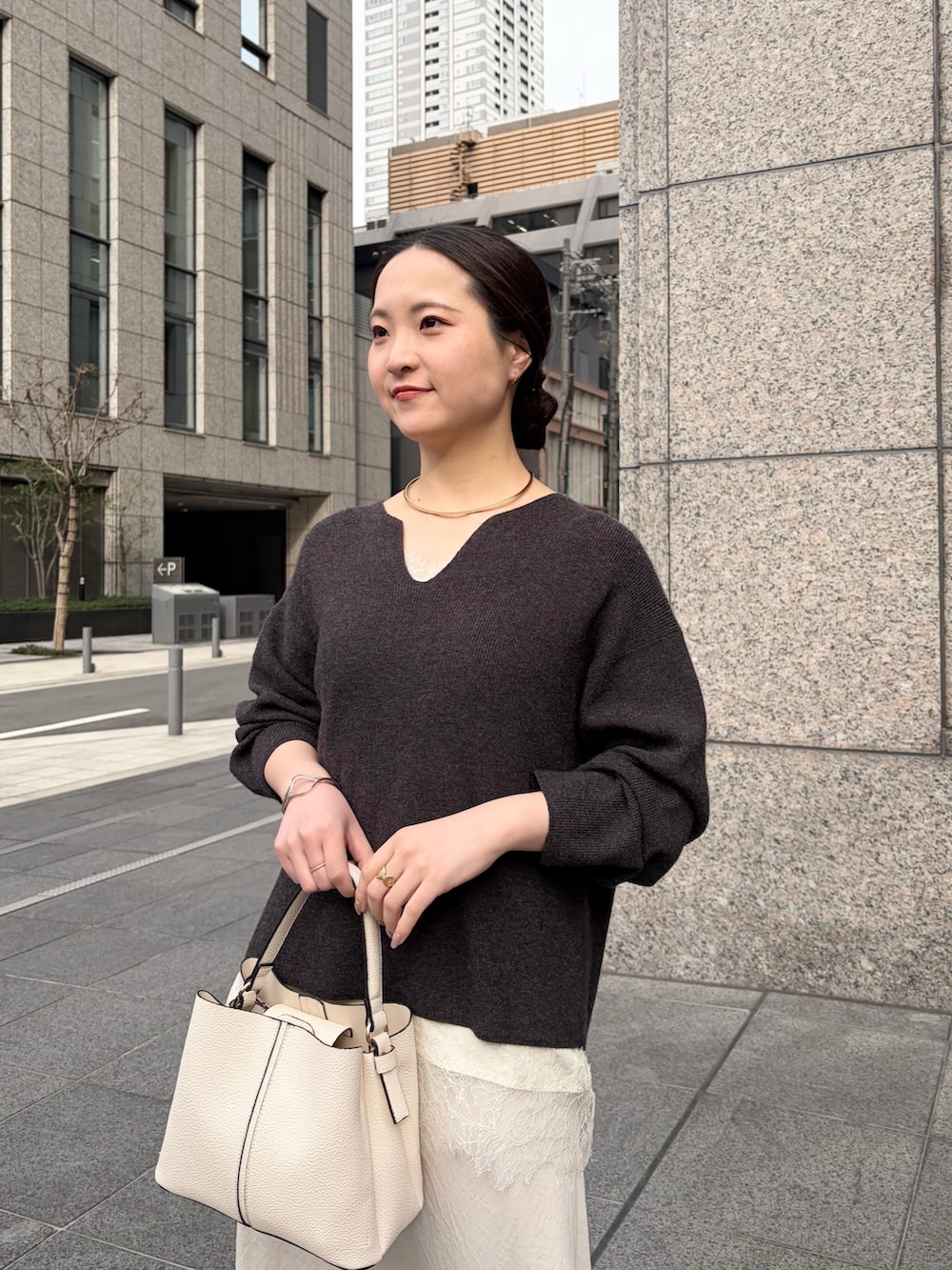 グレー系のニット/セーター、ホワイト系のシャツ/ブラウス、ホワイト系のスカートを着用したレディースの春コーディネートの4枚目の写真