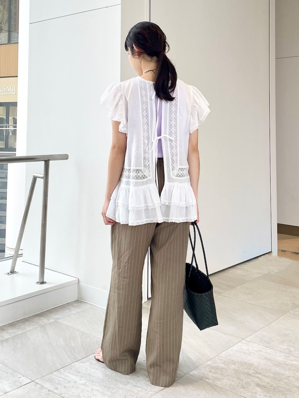 グリーン系のその他パンツ、ホワイト系のシャツ/ブラウス、パープル系のタンクトップを着用したレディースの春コーディネートの2枚目の写真