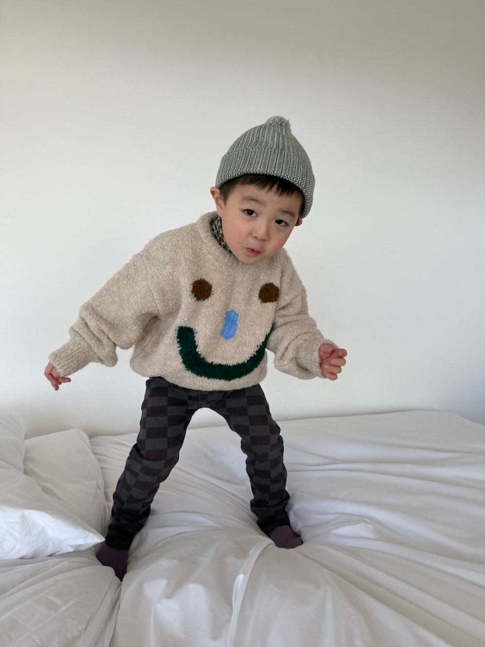 ベージュ系のニット/セーター、グレー系のパンツ、ブルー系のニットキャップ/ビーニーを着用したキッズの春コーディネートの2枚目の写真