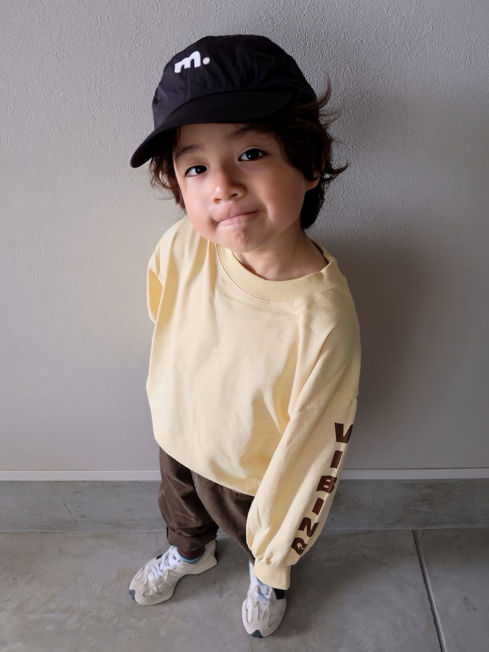 イエロー系のTシャツ/カットソー、ブラウン系のその他パンツ、ホワイト系のスニーカーを着用したキッズの秋コーディネートの2枚目の写真