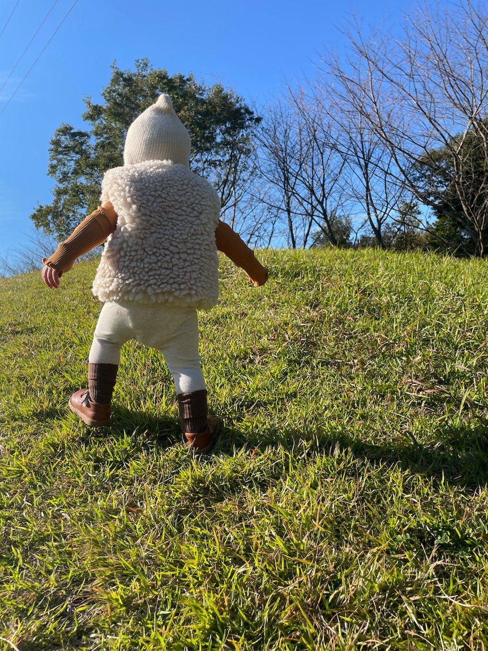 ホワイト系のベスト、ホワイト系のレギンス/スパッツ、ホワイト系のニットキャップ/ビーニーを着用したキッズの春コーディネートの2枚目の写真