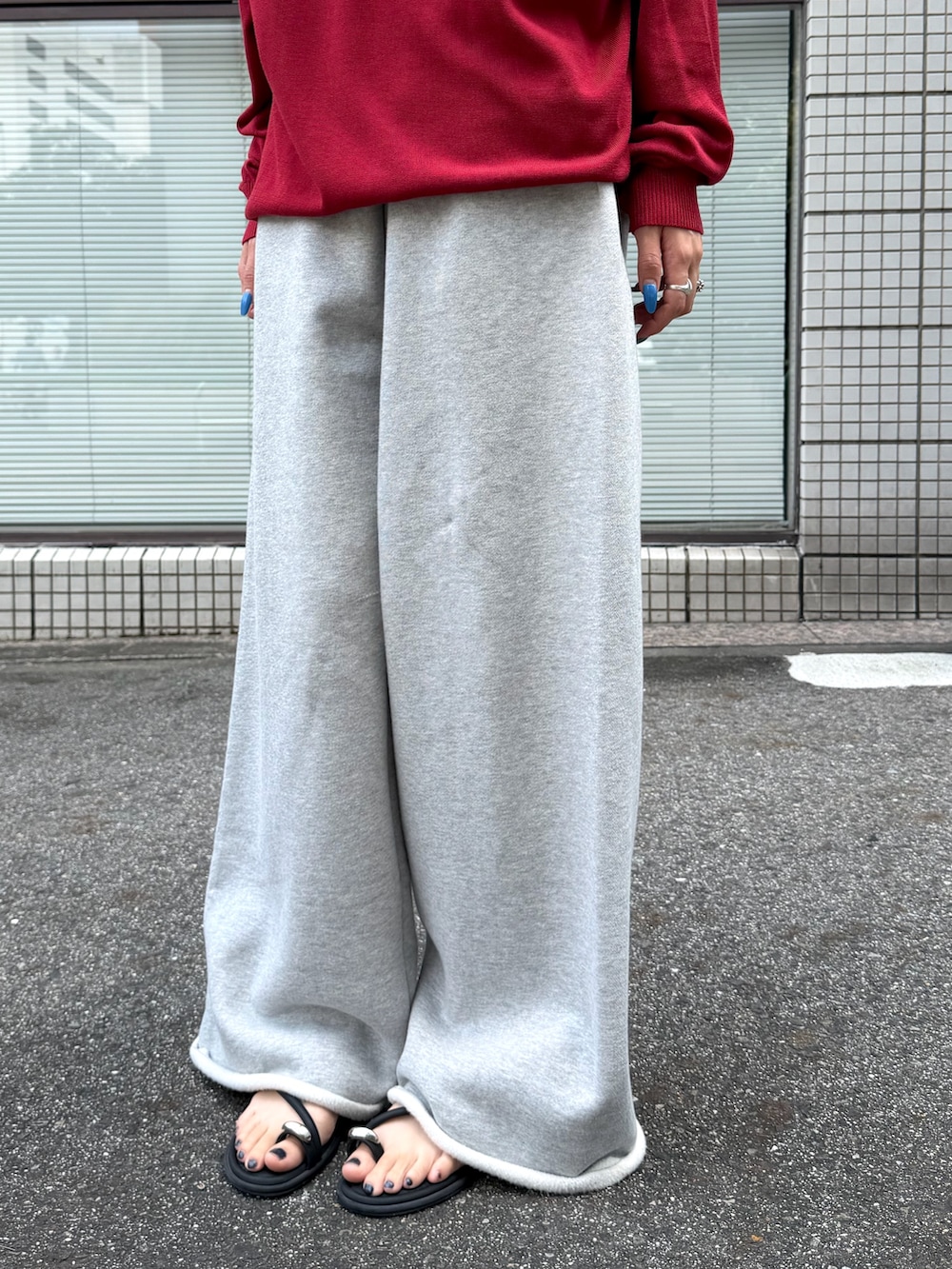 レッド系のポロシャツ、シルバー系のスウェットパンツ、ブラック系のサングラスを着用したレディースの夏コーディネートの2枚目の写真