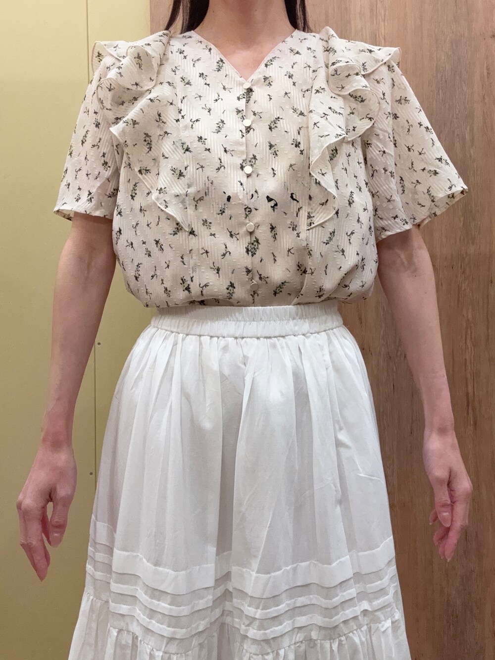 ブラウン系のパンプス、ホワイト系のスカート、ゴールド系のイヤリングを着用したレディースの春コーディネートの4枚目の写真