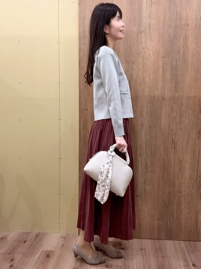 グレー系のカーディガン/ボレロ、レッド系のスカート、グレー系のハンドバッグを着用したレディースの冬コーディネートの2枚目の写真
