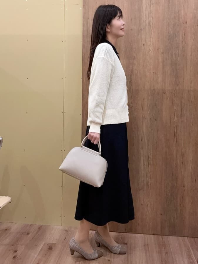 ブラウン系のパンプス、グレー系のハンドバッグ、ブルー系のワンピースを着用したレディースの冬コーディネートの2枚目の写真