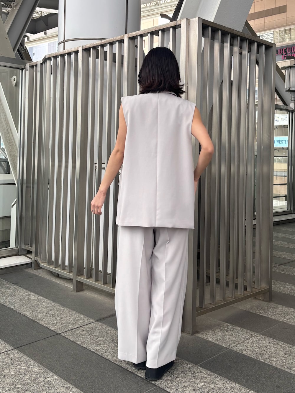 ベージュ系のスラックス、ベージュ系のベスト、オレンジ系のニット/セーターを着用したレディースの春コーディネートの3枚目の写真