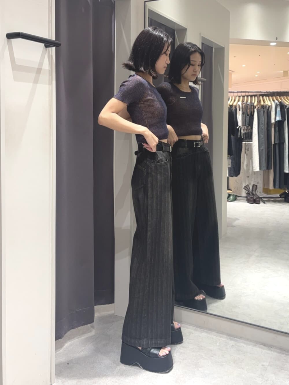 ブルー系のニット/セーター、ブラック系のデニムパンツ、ブラック系のブーツを着用したレディースの夏コーディネートの2枚目の写真