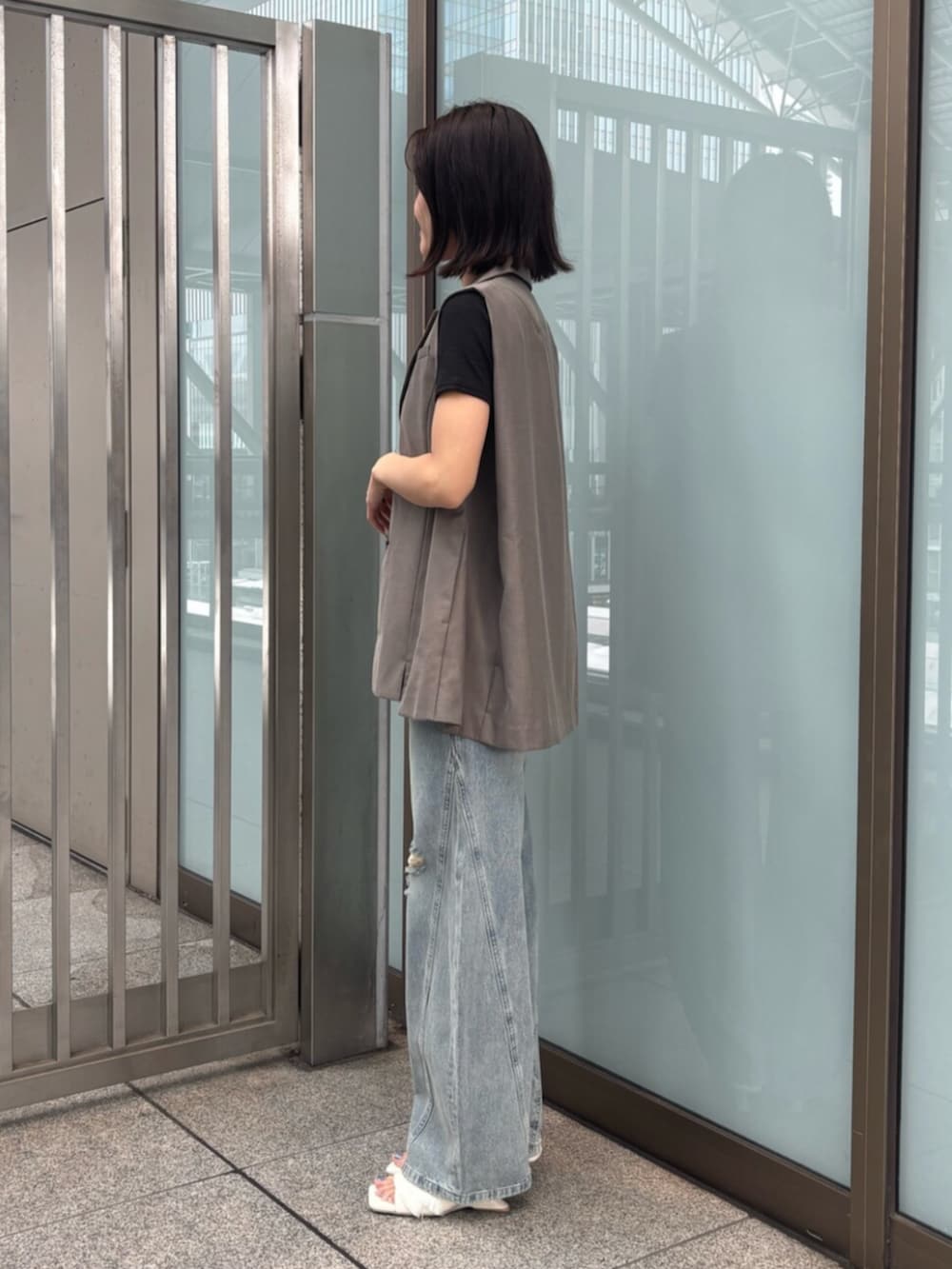 ホワイト系のサンダル、ブラック系のTシャツ/カットソー、ブラウン系のベストを着用したレディースの夏コーディネートの2枚目の写真