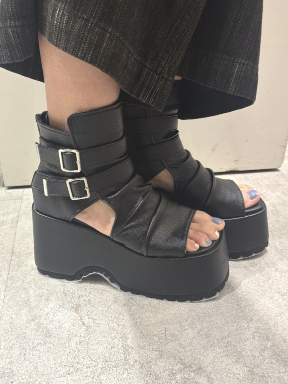 ブルー系のニット/セーター、ブラック系のデニムパンツ、ブラック系のブーツを着用したレディースの夏コーディネートの6枚目の写真