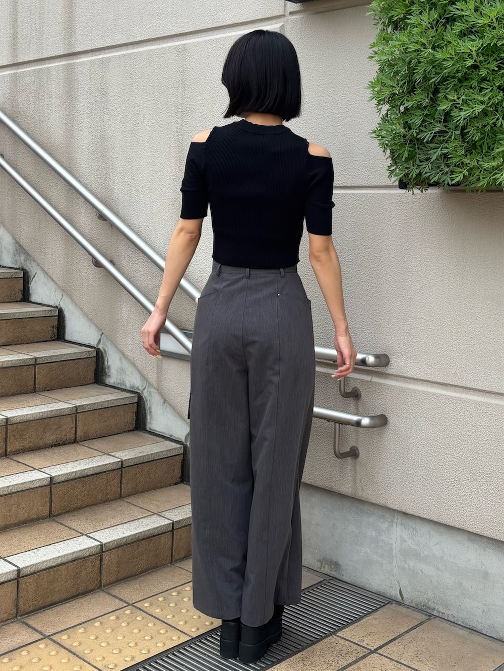 グレー系のスラックス、ブラック系のニット/セーター、ブラック系のブーツを着用したレディースの春コーディネートの3枚目の写真