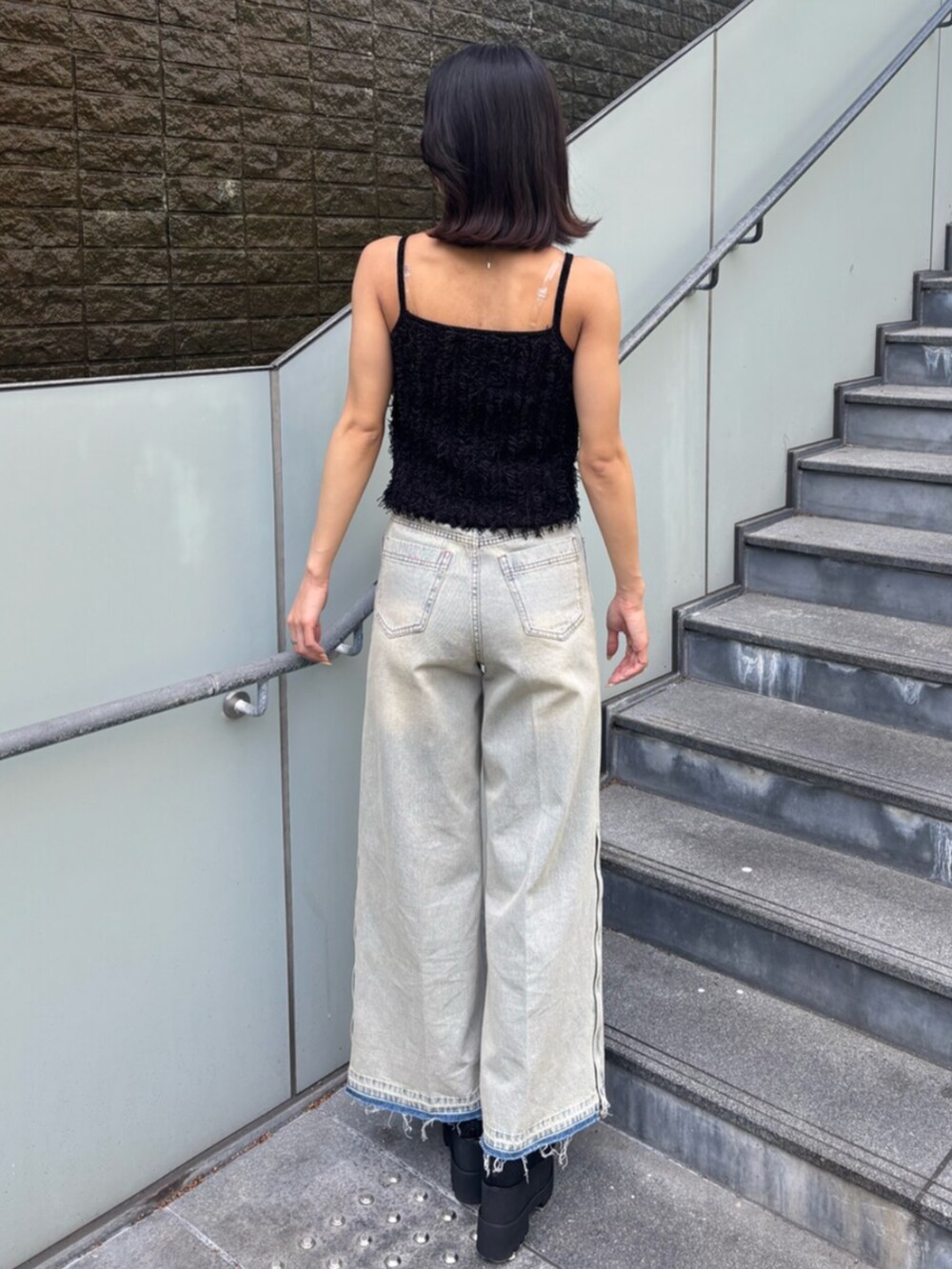 ブルー系のデニムパンツ、ブラック系のキャミソール、ブラック系のブーツを着用したレディースの春コーディネートの3枚目の写真