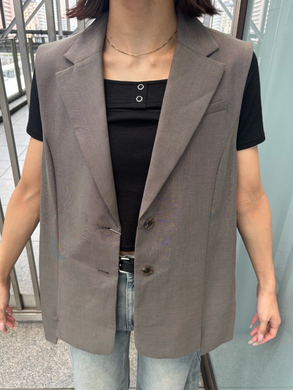 ホワイト系のサンダル、ブラック系のTシャツ/カットソー、ブラウン系のベストを着用したレディースの夏コーディネートの4枚目の写真