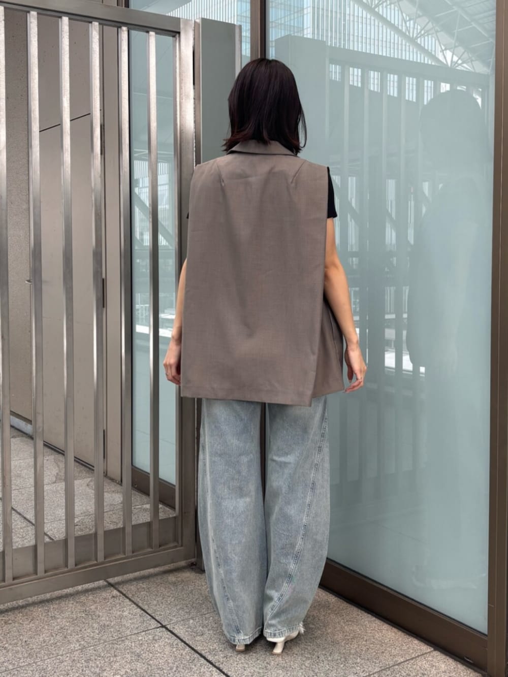 ホワイト系のサンダル、ブラック系のTシャツ/カットソー、ブラウン系のベストを着用したレディースの夏コーディネートの3枚目の写真