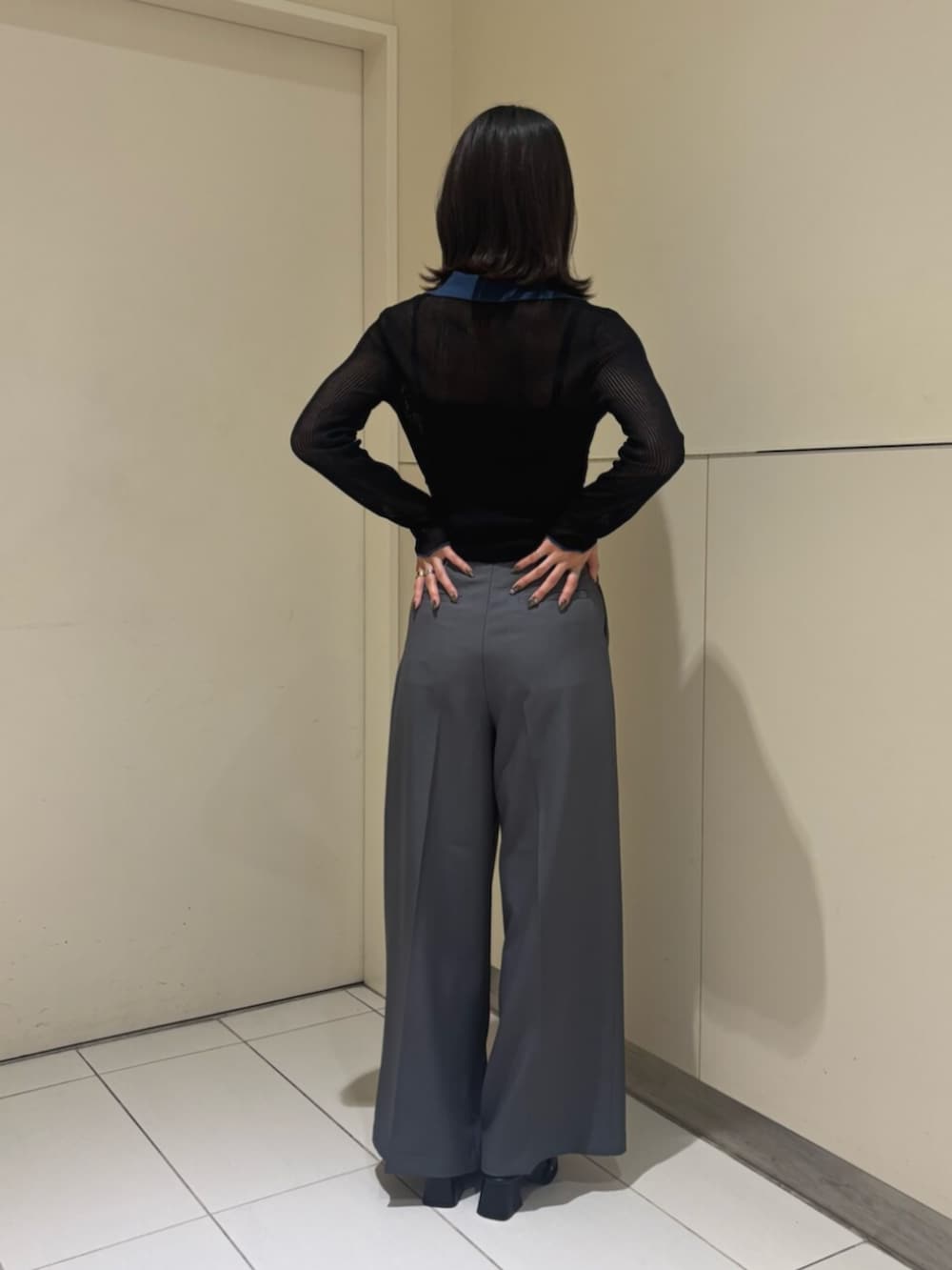 グレー系のスラックス、ブラック系のニット/セーター、ブラック系のパンプスを着用したレディースの秋コーディネートの4枚目の写真