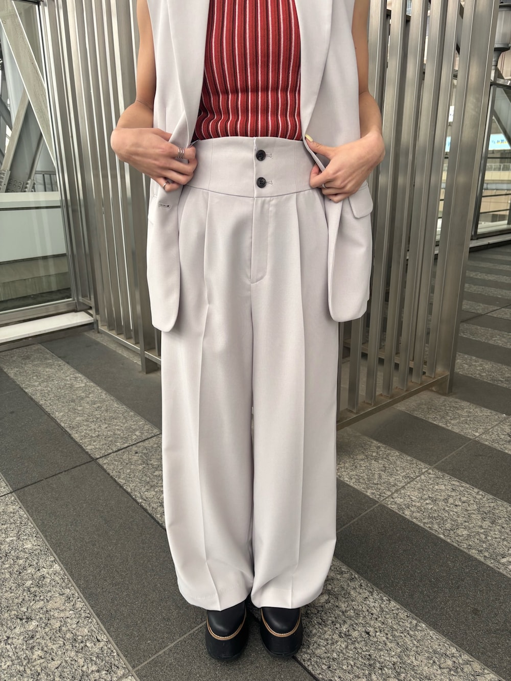 ベージュ系のスラックス、ベージュ系のベスト、オレンジ系のニット/セーターを着用したレディースの春コーディネートの6枚目の写真