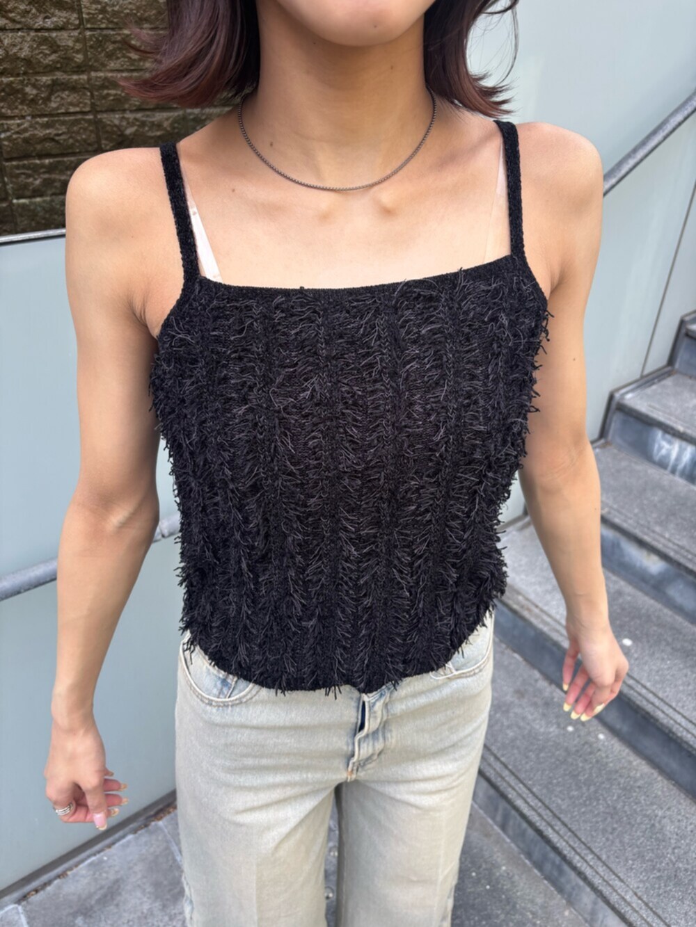 ブルー系のデニムパンツ、ブラック系のキャミソール、ブラック系のブーツを着用したレディースの春コーディネートの4枚目の写真