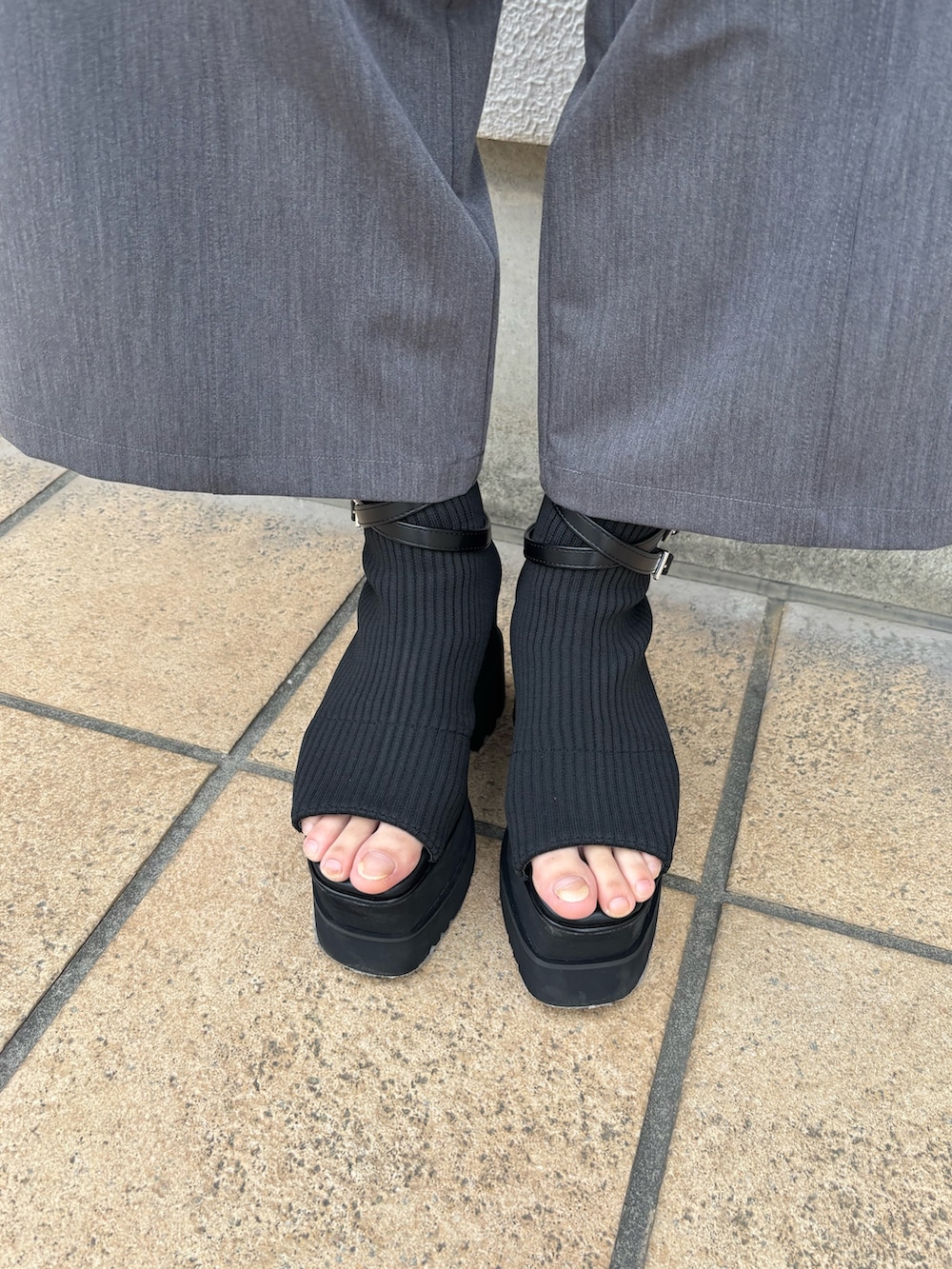 グレー系のスラックス、ブラック系のニット/セーター、ブラック系のブーツを着用したレディースの春コーディネートの6枚目の写真