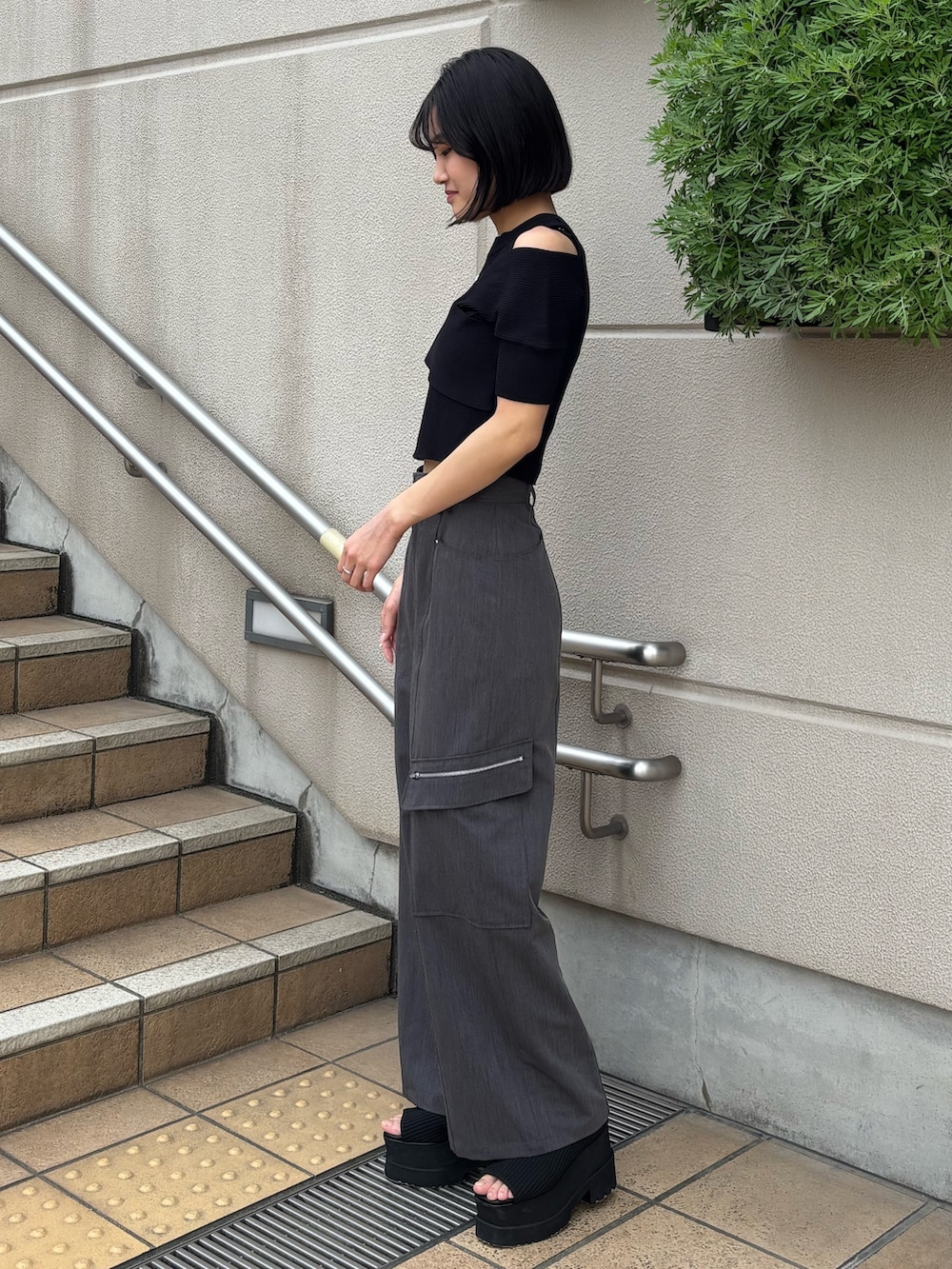グレー系のスラックス、ブラック系のニット/セーター、ブラック系のブーツを着用したレディースの春コーディネートの2枚目の写真