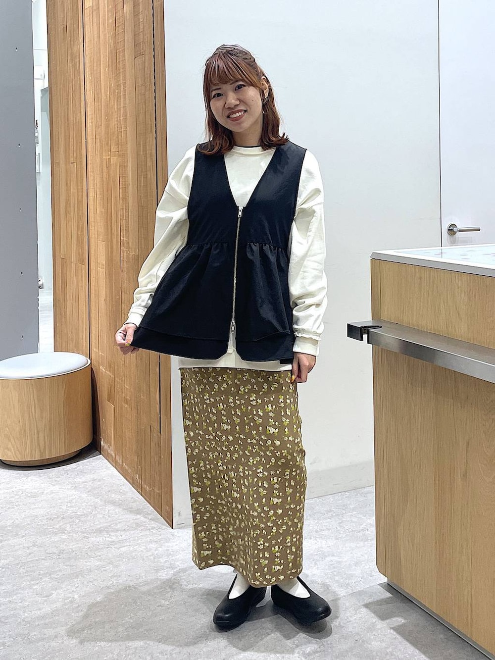 ホワイト系のスウェット、ブラック系のパンプス、ブラウン系のスカートを着用したレディースの冬コーディネートの4枚目の写真