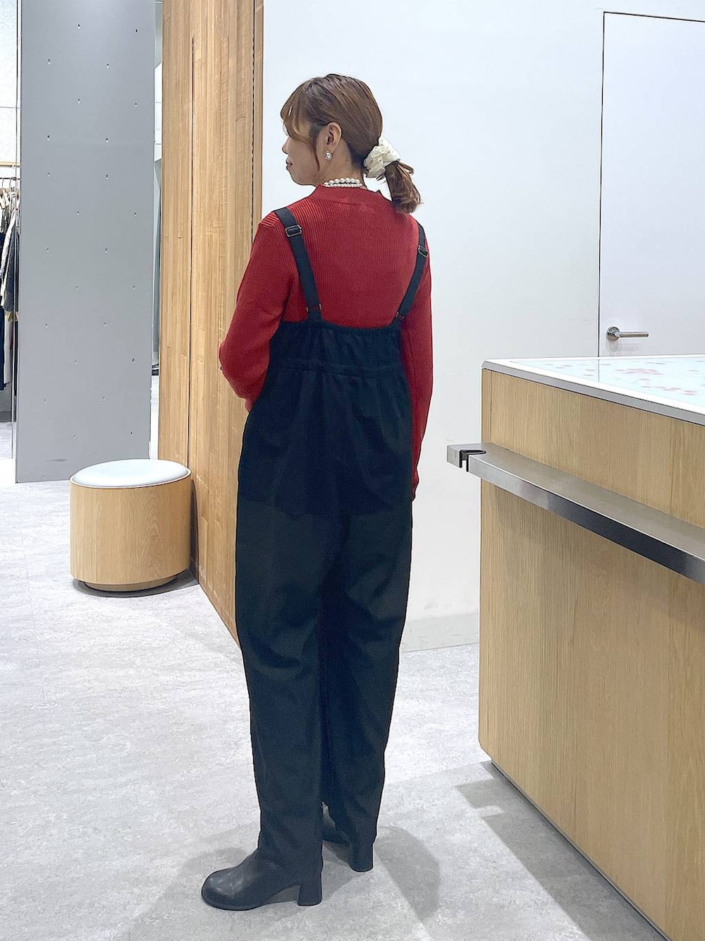 レッド系のニット/セーター、ブラック系のブーツ、ホワイト系のショルダーバッグを着用したレディースの冬コーディネートの5枚目の写真