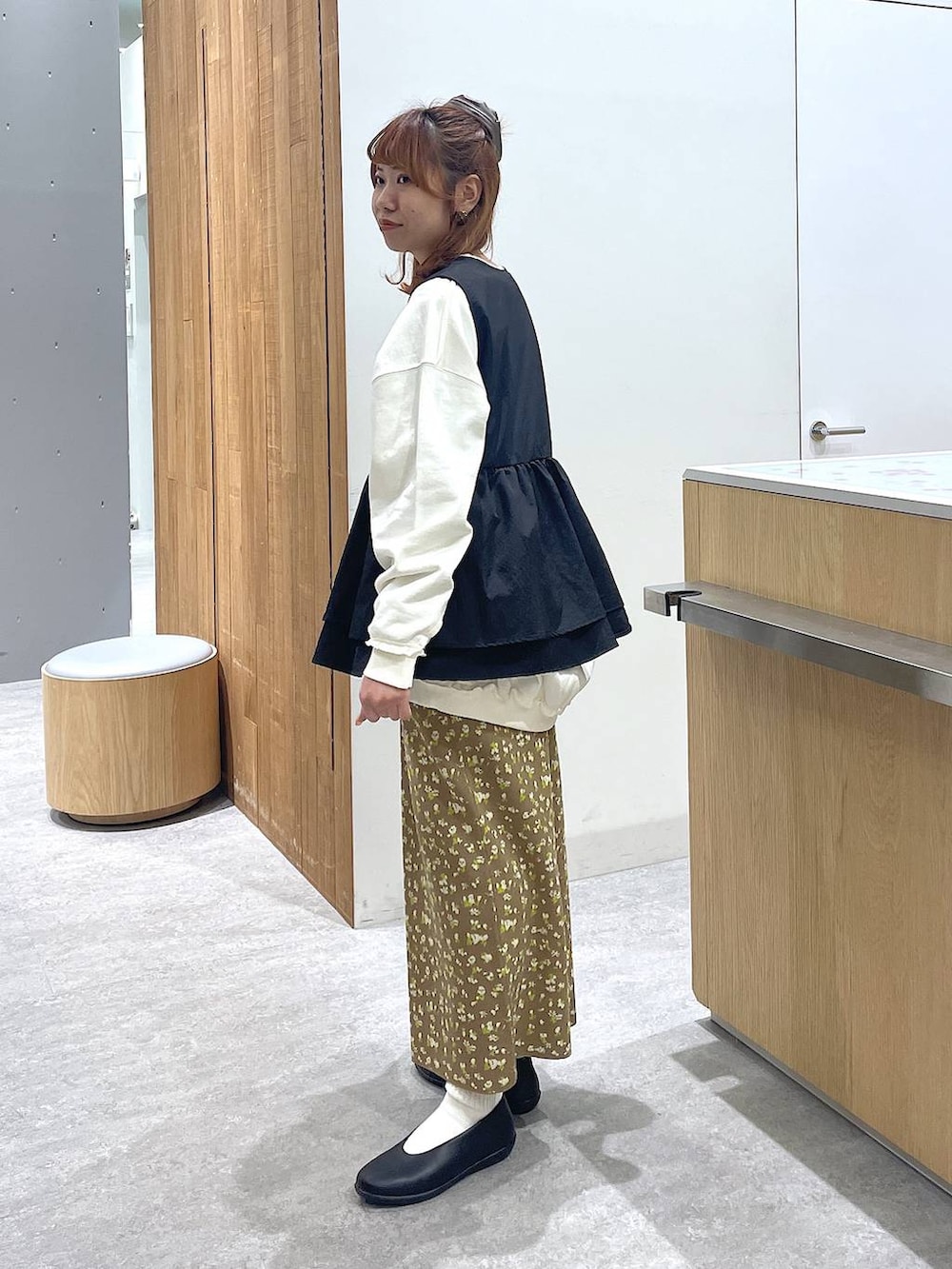 ホワイト系のスウェット、ブラック系のパンプス、ブラウン系のスカートを着用したレディースの冬コーディネートの2枚目の写真