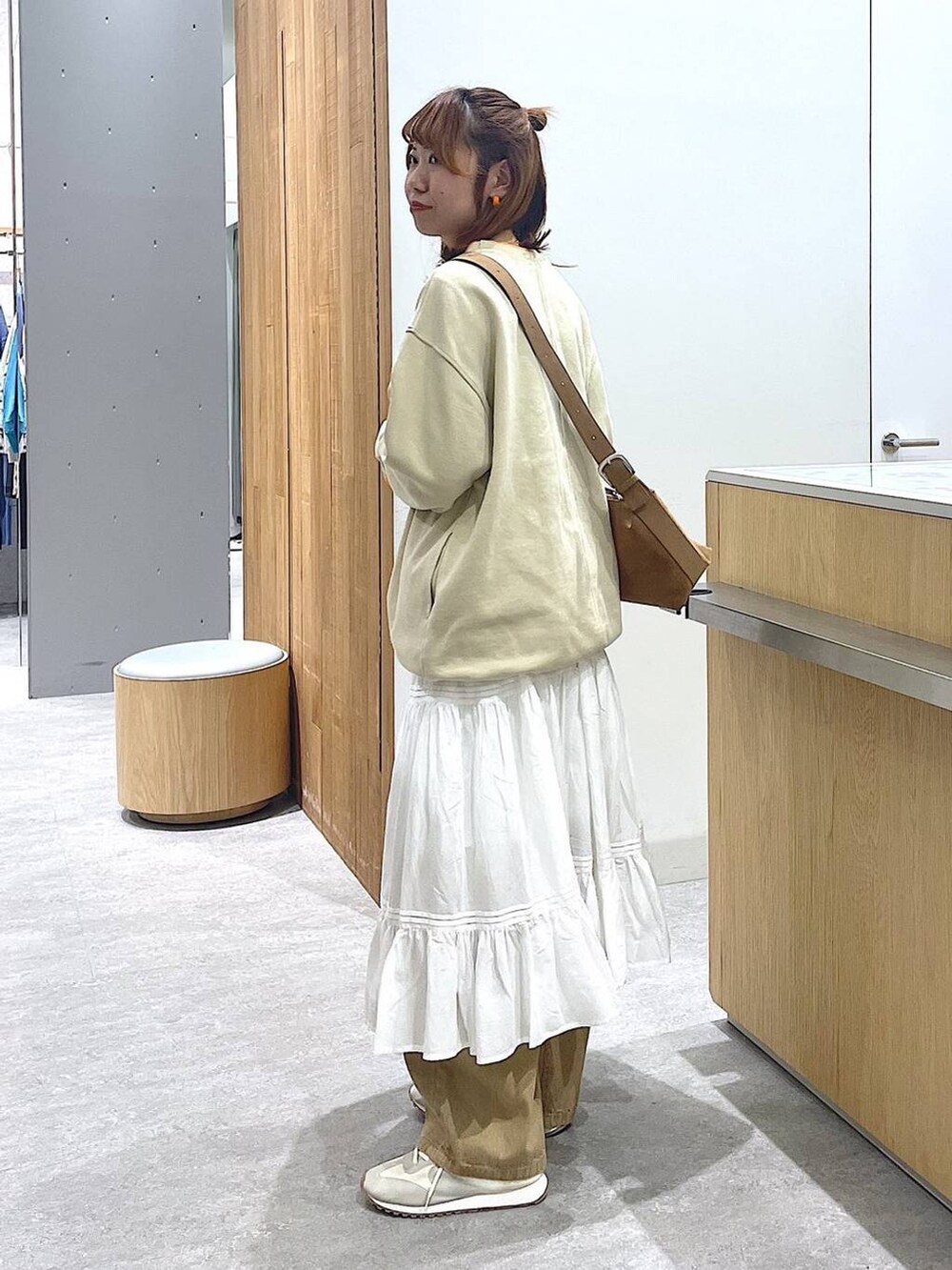 ブラウン系のショルダーバッグ、ベージュ系のその他パンツ、ホワイト系のスニーカーを着用したレディースの冬コーディネートの2枚目の写真