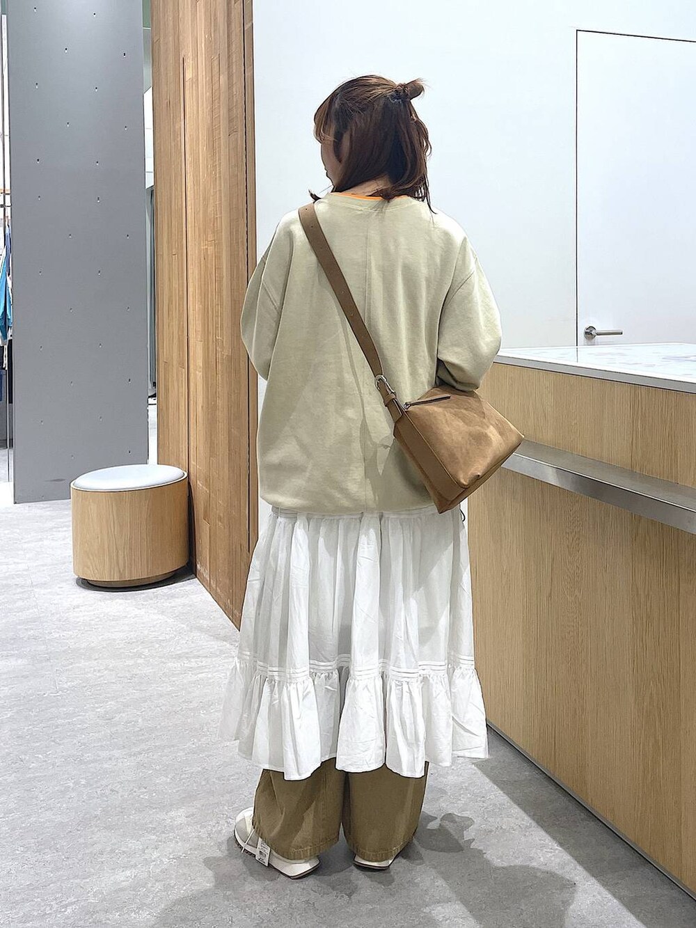 ブラウン系のショルダーバッグ、ベージュ系のその他パンツ、ホワイト系のスニーカーを着用したレディースの冬コーディネートの3枚目の写真