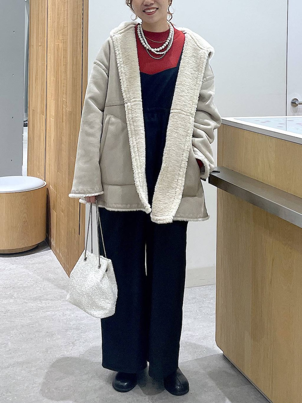 レッド系のニット/セーター、ブラック系のブーツ、ホワイト系のショルダーバッグを着用したレディースの冬コーディネートの6枚目の写真