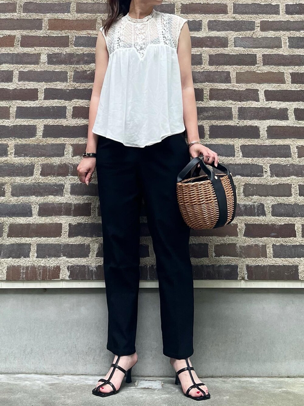 ブラック系のスラックス、ブラック系のサンダルを着用したレディースの夏コーディネートの2枚目の写真