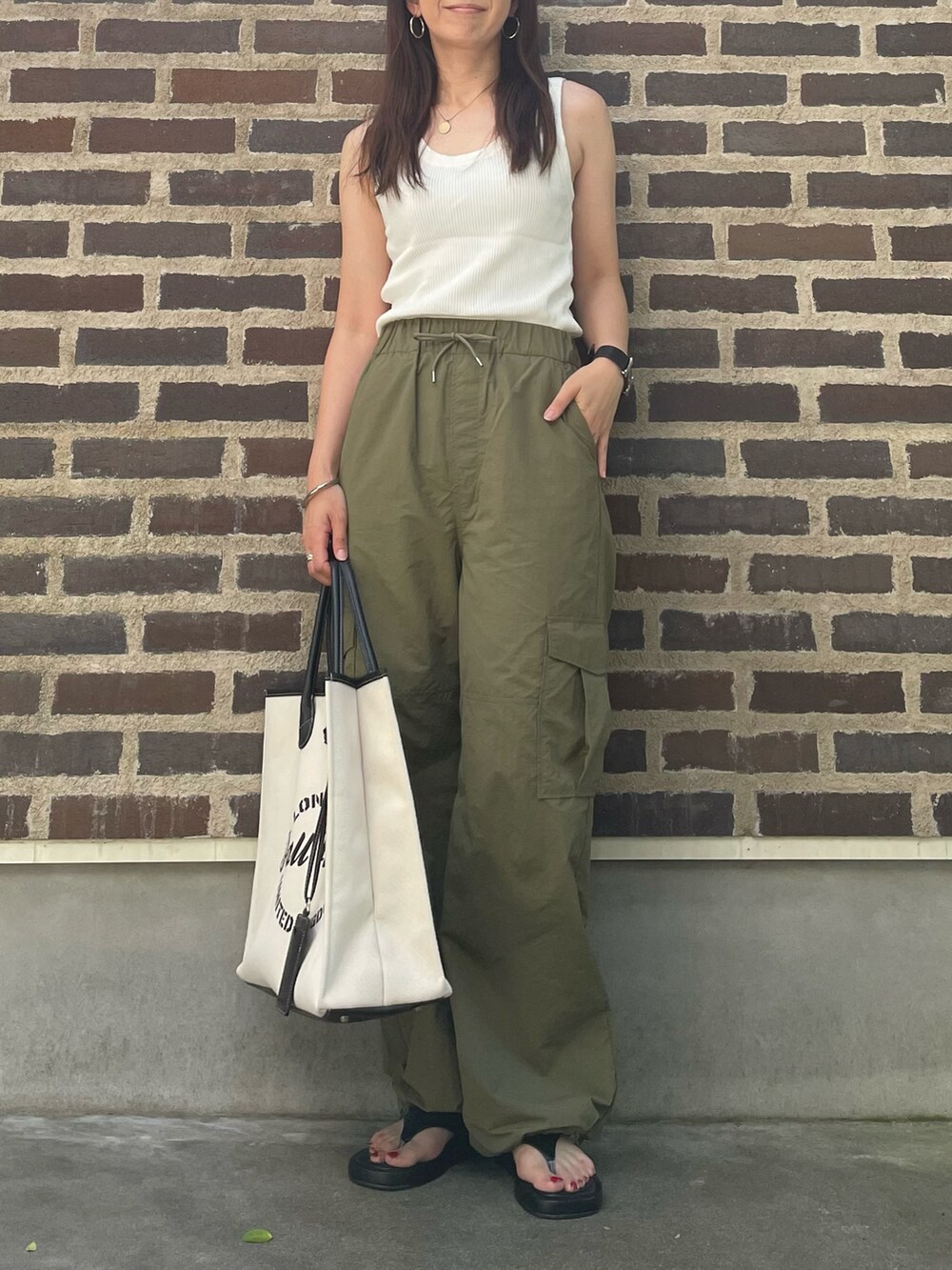グリーン系のカーゴパンツ、ブラック系のバッグ、ブラック系のサンダルを着用したレディースの夏コーディネートの3枚目の写真