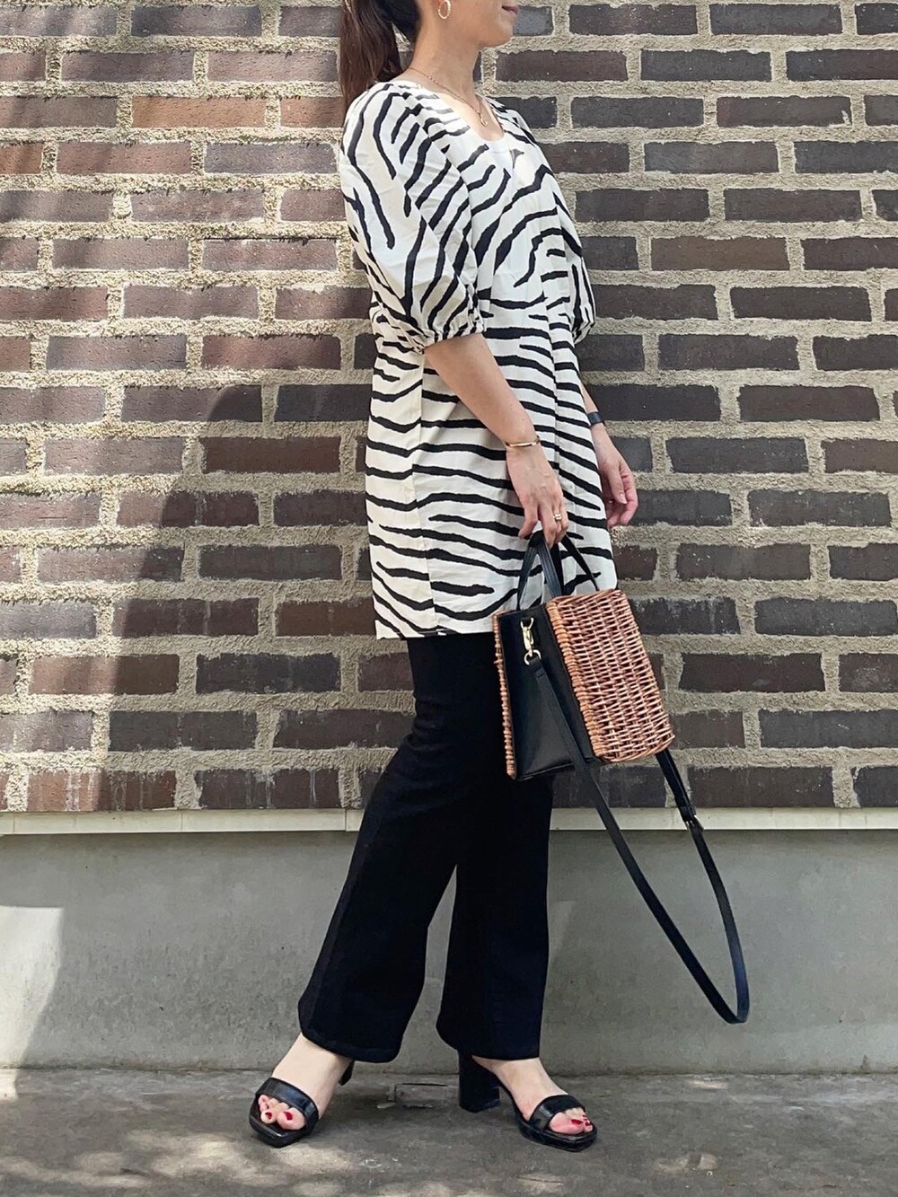 その他のチュニック、ブラック系のデニムパンツ、ブラック系のサンダルを着用したレディースの夏コーディネートの3枚目の写真