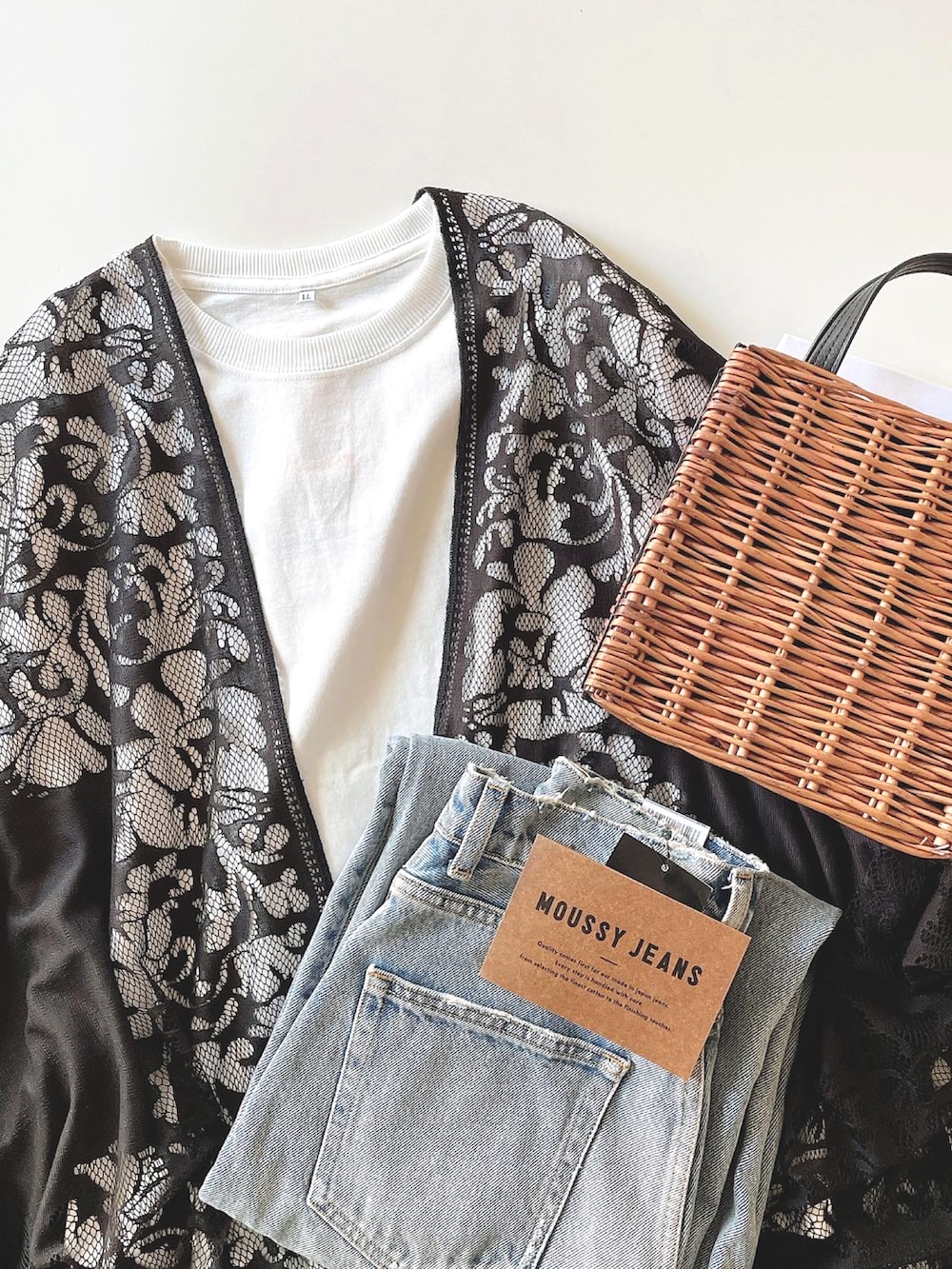 ホワイト系のタンクトップ、ブラック系のポンチョ、ブルー系のデニムパンツを着用したレディースの春コーディネートの4枚目の写真