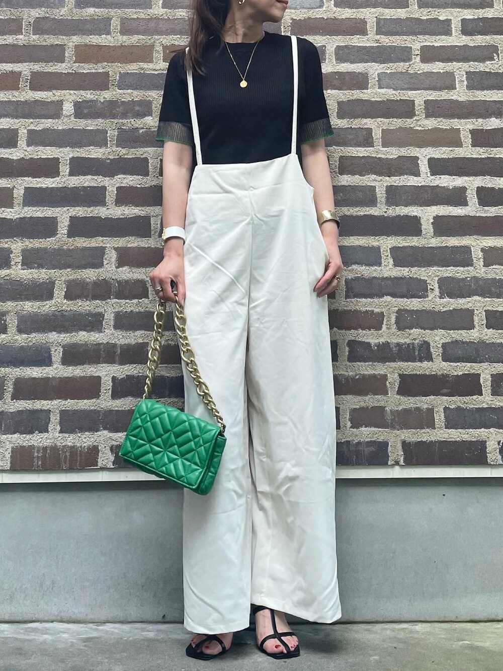 ブラック系のニット/セーター、ホワイト系のサロペット/オーバーオール、ブラック系のサンダルを着用したレディースの夏コーディネートの3枚目の写真