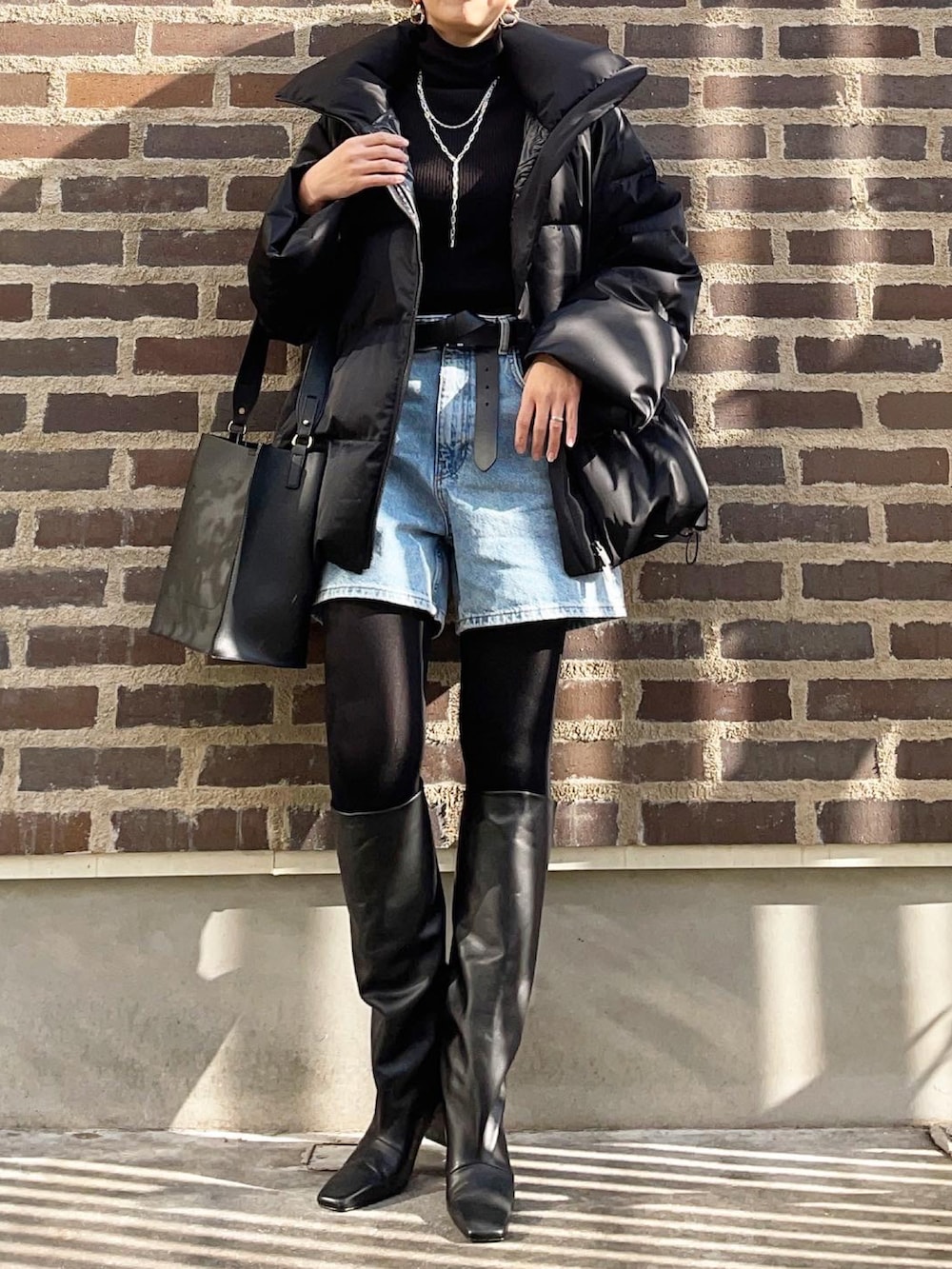 ブラック系のニット/セーター、ブルー系のデニムパンツ、ブラック系のブーツを着用したレディースの冬コーディネートの2枚目の写真