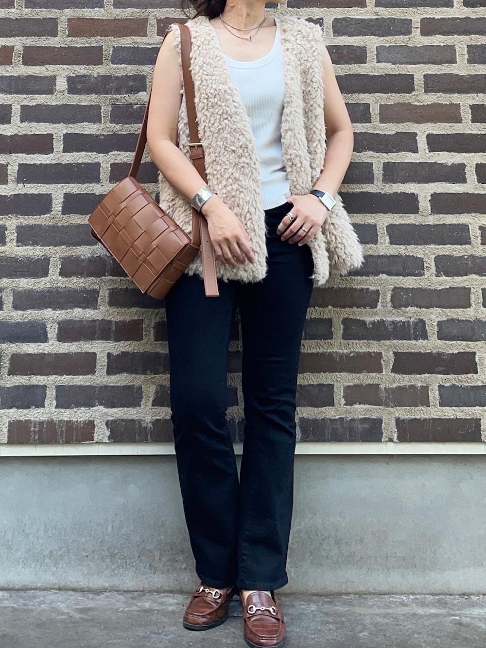 ブラック系のデニムパンツ、ブラウン系のローファー、ブラウン系のショルダーバッグを着用したレディースの秋コーディネートの2枚目の写真