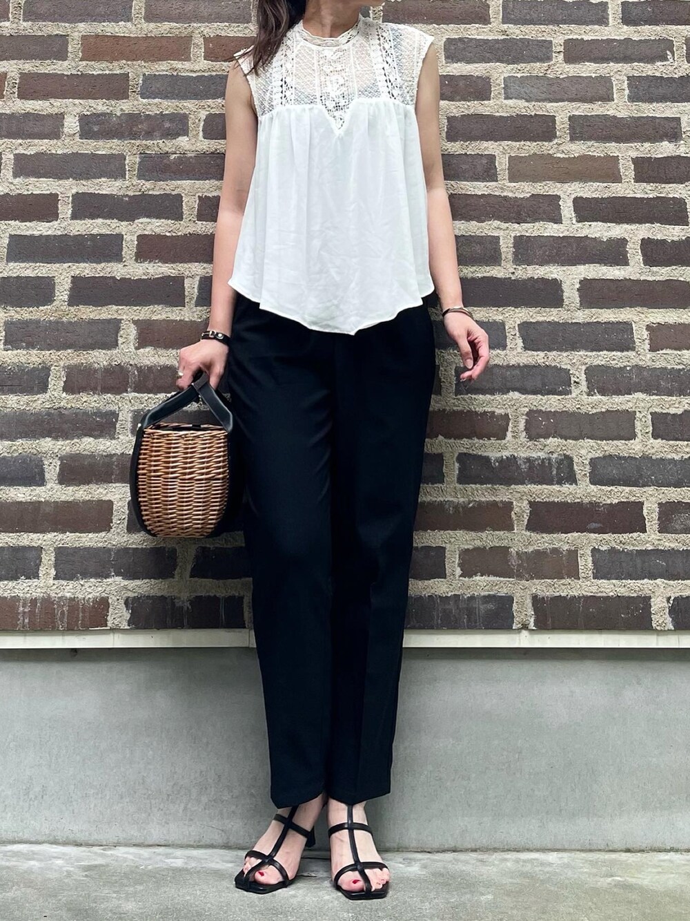 ブラック系のスラックス、ブラック系のサンダルを着用したレディースの夏コーディネートの3枚目の写真