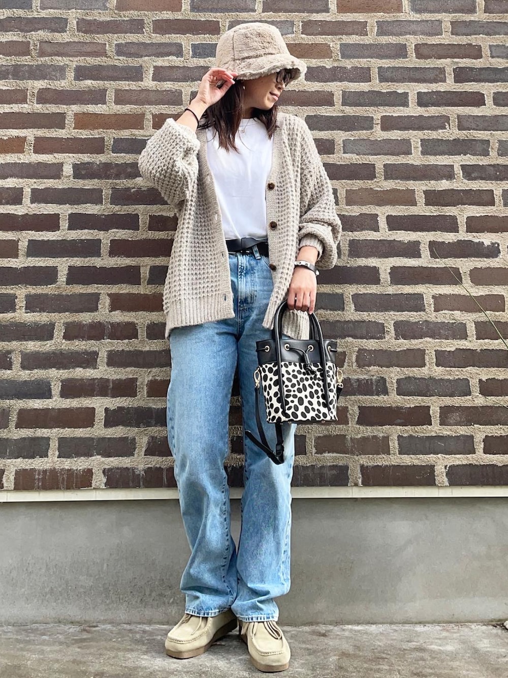 ブラック系のショルダーバッグ、ベージュ系のモカシン/デッキシューズ、ブルー系のデニムパンツを着用したレディースの秋コーディネートの3枚目の写真