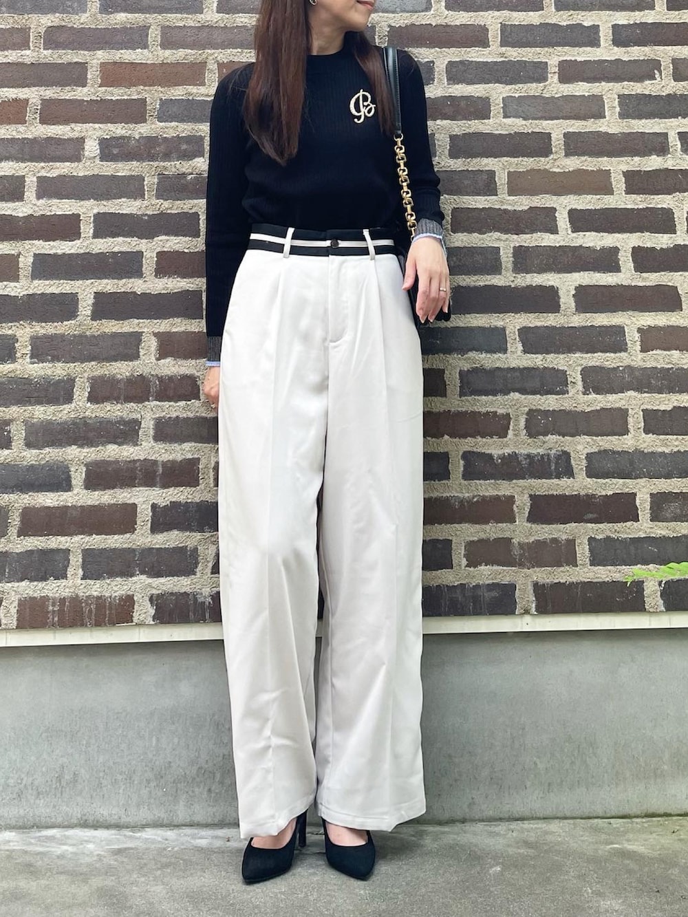 ブラック系のニット/セーター、ホワイト系のスラックス、ブラック系のパンプスを着用したレディースの秋コーディネートの3枚目の写真