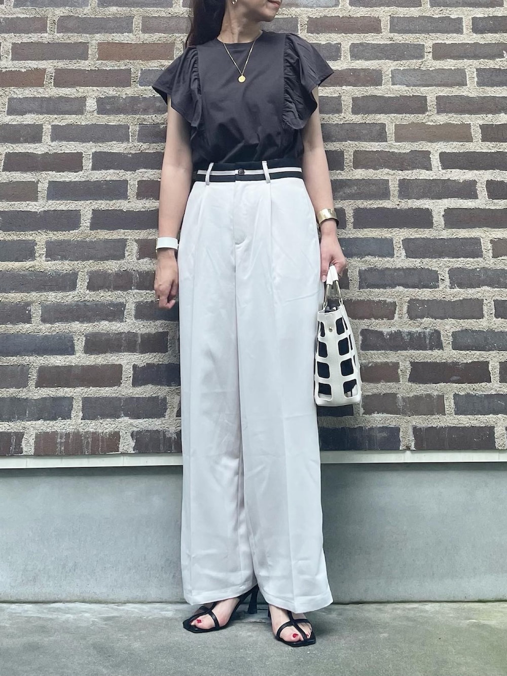 グレー系のTシャツ/カットソー、ホワイト系のスラックス、ブラック系のサンダルを着用したレディースの夏コーディネートの2枚目の写真