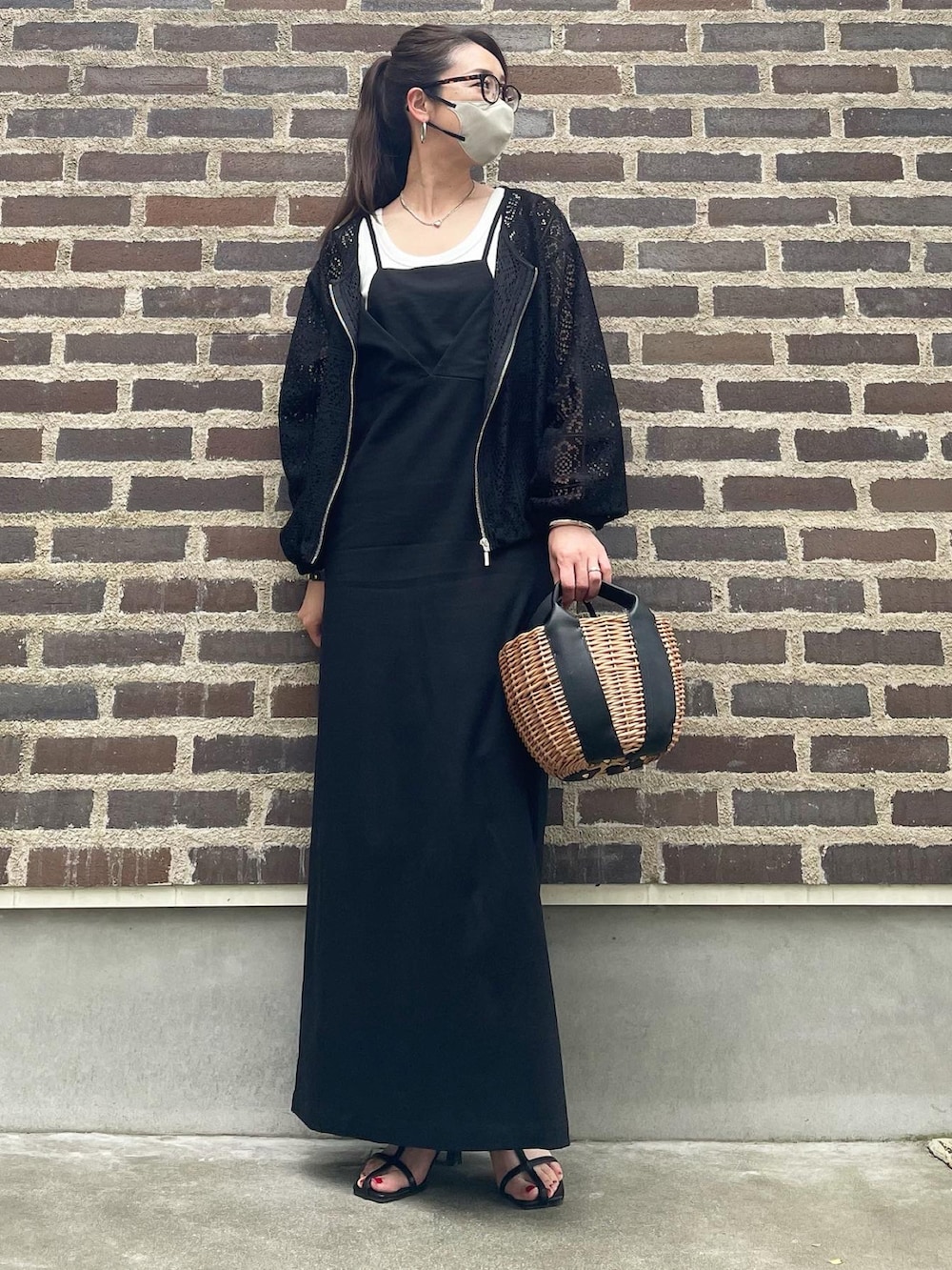 ベージュ系のかごバッグ、ブラック系のサンダル、ブラック系のワンピースを着用したレディースの春コーディネートの2枚目の写真