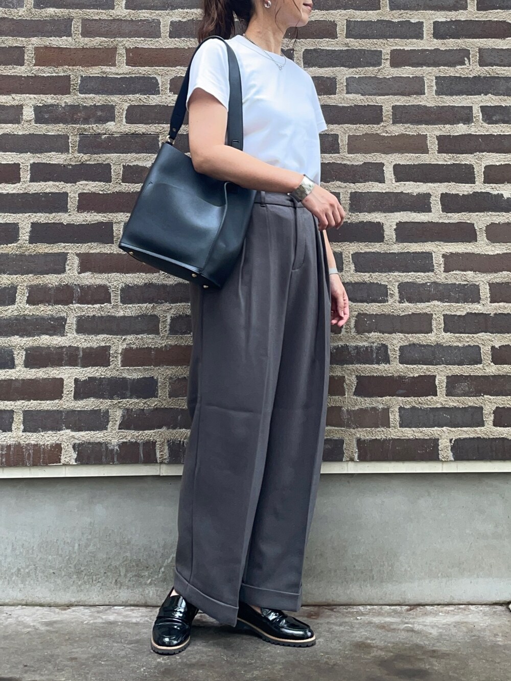 グレー系のスラックス、シルバー系のアナログ腕時計を着用したレディースの秋コーディネートの2枚目の写真