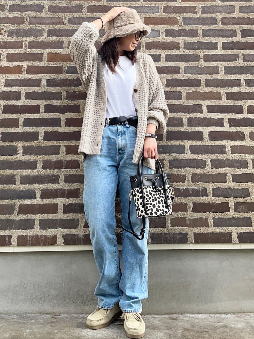 ブラック系のショルダーバッグ、ベージュ系のモカシン/デッキシューズ、ブルー系のデニムパンツを着用したレディースの秋コーディネートの2枚目の写真