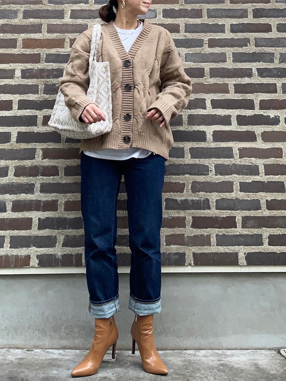 ベージュ系のカーディガン/ボレロ、ブルー系のデニムパンツ、ブラウン系のブーツを着用したレディースの秋コーディネートの2枚目の写真