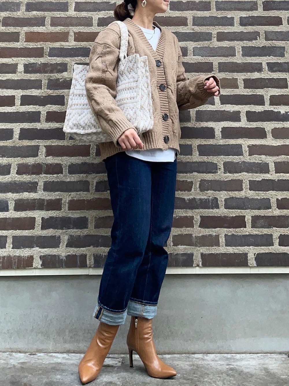 ベージュ系のカーディガン/ボレロ、ブルー系のデニムパンツ、ブラウン系のブーツを着用したレディースの秋コーディネートの3枚目の写真