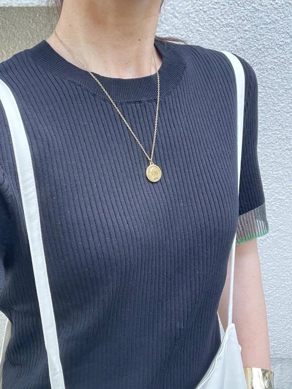 ブラック系のニット/セーター、ホワイト系のサロペット/オーバーオール、ブラック系のサンダルを着用したレディースの夏コーディネートの4枚目の写真