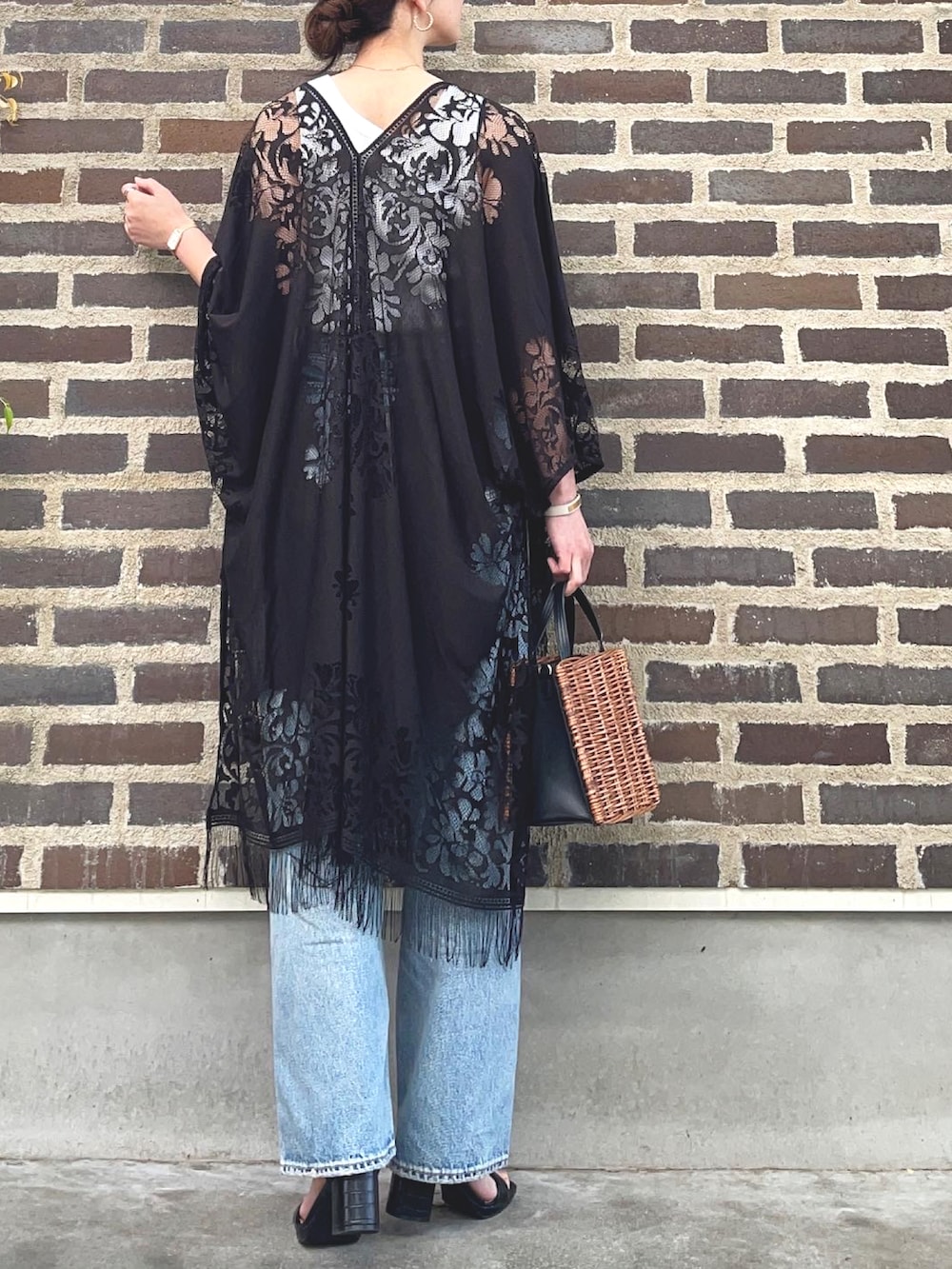 ホワイト系のタンクトップ、ブラック系のポンチョ、ブルー系のデニムパンツを着用したレディースの春コーディネートの3枚目の写真