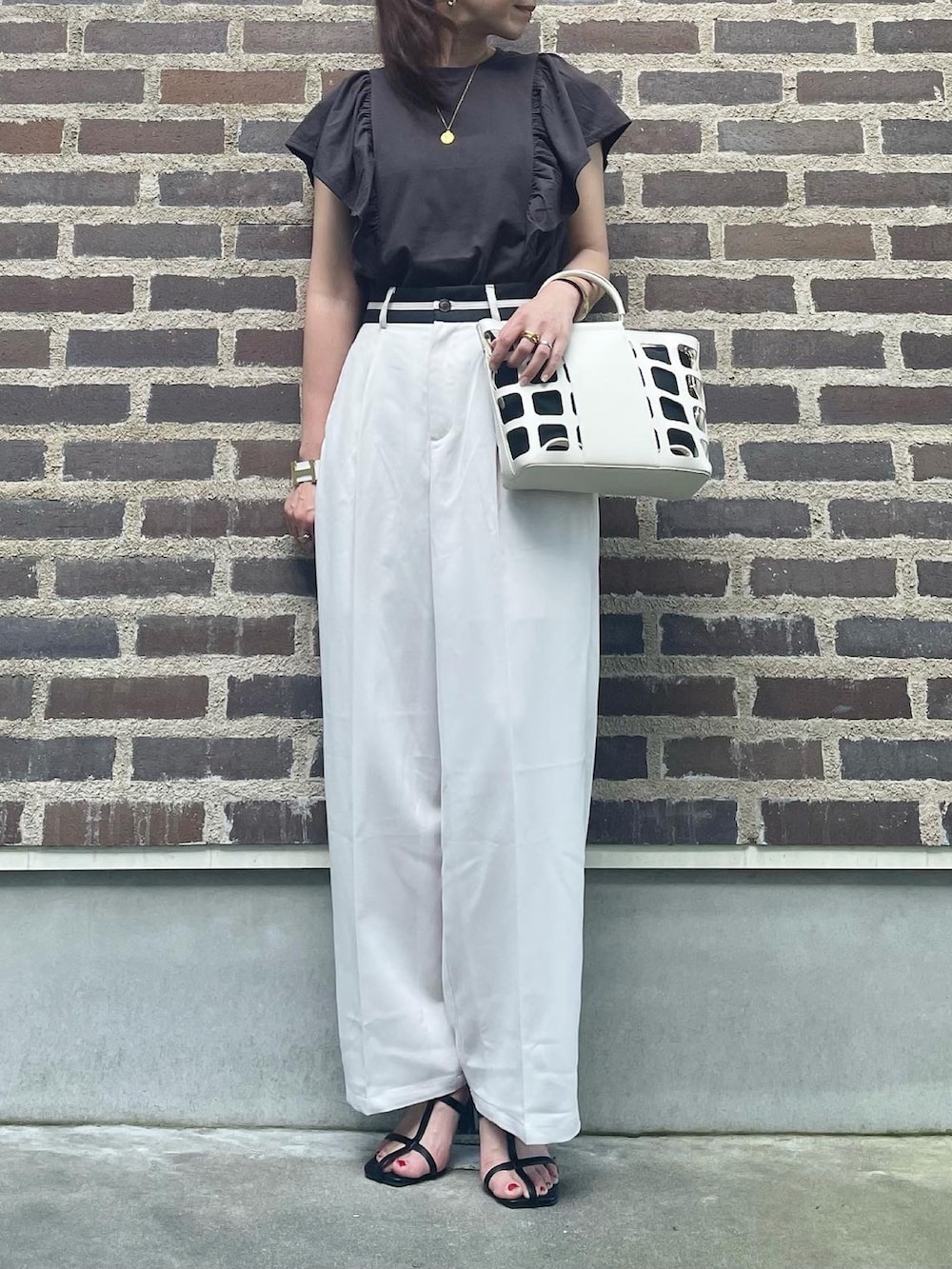 グレー系のTシャツ/カットソー、ホワイト系のスラックス、ブラック系のサンダルを着用したレディースの夏コーディネートの3枚目の写真